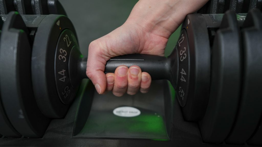 BarBend tester adjusting the Flybird Fitness adjustable dumbbell.