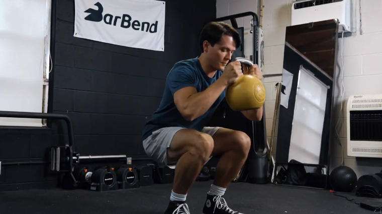 A fit person performing the goblet squat exercise with the Bells of Steel Competition Kettlebell.