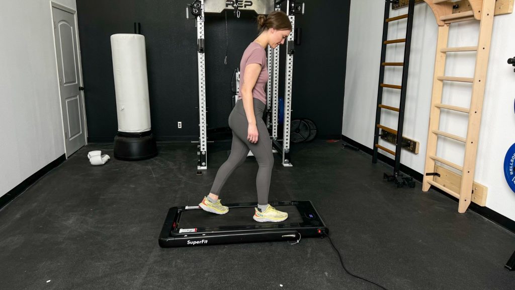 A woman walking on the Goplus 2 in 1 Folding Treadmillwith the handlebar down